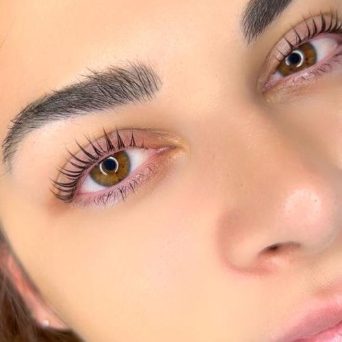 Primer plano de una joven con ojos marrones y pestañas largas, mostrando un maquillaje sutil y piel radiante. Ideal para temas de belleza y cuidado personal.